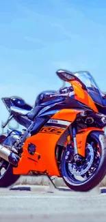 Vibrant orange motorcycle on road with clear sky.