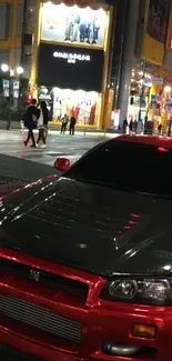 Red car under Tokyo city lights at night.