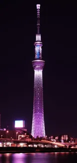 Tokyo Skytree illuminated at night with purple hues reflecting on river.