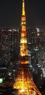 Tokyo Tower glowing at night amidst city lights.