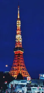 Tokyo Tower illuminated at night with vibrant blue sky.