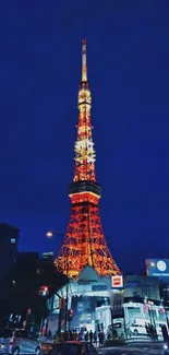 Tokyo Tower illuminated at night against a dark blue cityscape.