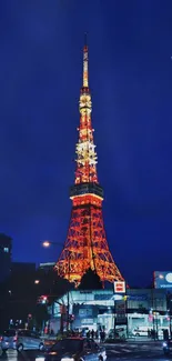 Illuminated Tokyo Tower at night with vibrant blue sky.