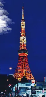 Tokyo Tower illuminated against a deep blue night sky with vibrant city lights.