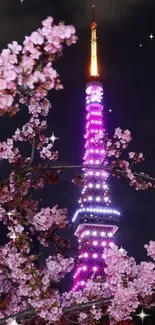 Tokyo Tower glowing behind cherry blossoms at night.