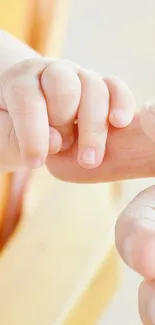 Close-up of a newborn's hand holding an adult finger, with soft beige background.