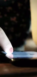 Close-up of a hand interacting with a smartphone in low light.