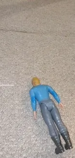 Toy action figure on textured carpet wallpaper.