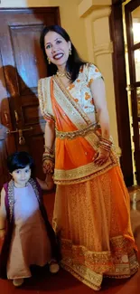 Mother and child in traditional Indian attire with vibrant orange dress.