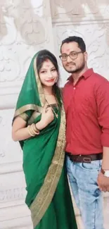 Couple in traditional attire with vibrant colors on a decorative background.