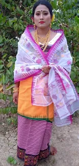 Assamese woman in traditional attire with vibrant colors and nature background.