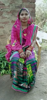 Woman in traditional Indian attire seated in rural setting.