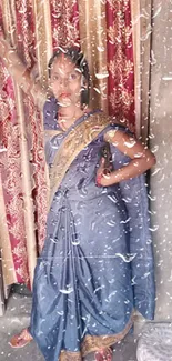 Woman in blue saree poses against a rustic wall.