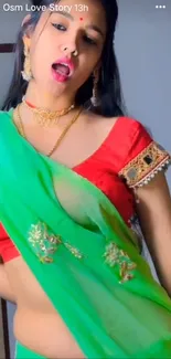 Woman in vibrant traditional attire with green saree and red blouse.