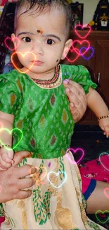 Baby in vibrant green traditional attire.