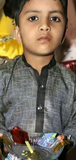 Child in traditional festive attire holding a decorative platter.