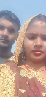 Couple in traditional dress under a clear blue sky.