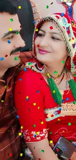 Smiling couple in traditional red attire with vibrant cultural elements.