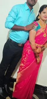 Couple in traditional attire with vibrant saree and golden jewelry.