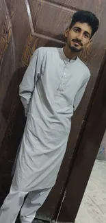 Man in traditional attire stands by a wooden door.