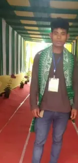 Man standing on red carpet with green and yellow backdrop.