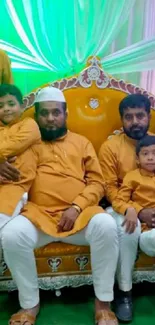 Family in traditional attire sitting on an ornate chair with colorful floral backdrop.