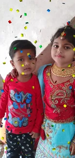 Two children in colorful traditional attire, posing together indoors.