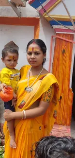 A woman and child in vibrant traditional attire outside a colorful building.