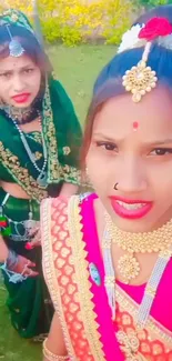 Two women in colorful traditional Indian attire and jewelry outdoors.