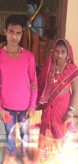 Couple in traditional red Indian attire with historical backdrop.