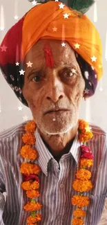 Traditional Indian man with orange turban and marigold garland.