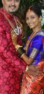 Smiling couple in colorful Indian wedding attire.