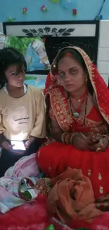 Indian bride with child in traditional attire on a colorful bed.