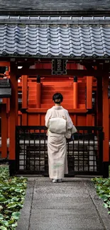 Woman in kimono at a vibrant red Japanese shrine.