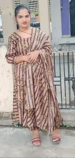 Woman in a traditional brown dress posing outdoors.