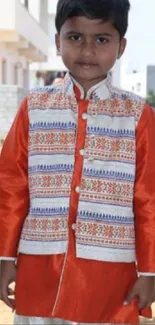 Boy in vibrant traditional attire on sunny day.