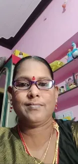 Woman in traditional attire with pink background.