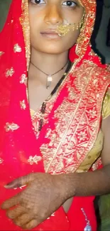 Woman in red and gold traditional bridal attire with henna on hand.