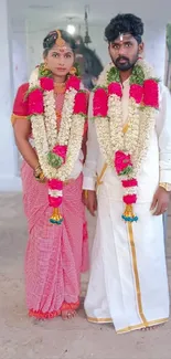 Traditional wedding couple in vibrant attire with floral garlands.