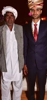 Two men in traditional wedding attire pose for the camera.