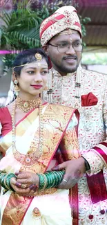 Traditional wedding couple in vibrant attire posing elegantly.