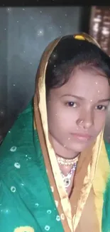 A woman wearing a green sari sits in a traditional setting.