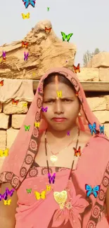 Woman in pink traditional attire standing in front of brick wall.