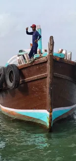 A traditional wooden boat sails on calm, teal sea waters under a clear sky.