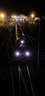 A night train with bright lights on dark tracks.