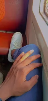 Hand on jeans inside train with window view