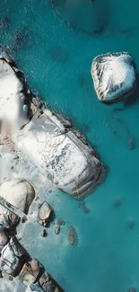 Aerial view of turquoise ocean with rocks.