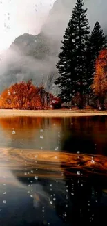 Tranquil autumn lake with misty mountains and trees reflecting in water.