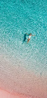 Aerial view of a serene beach with turquoise waters and pink sand.