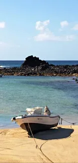 A boat on golden sand by a tranquil blue sea under a clear sky.